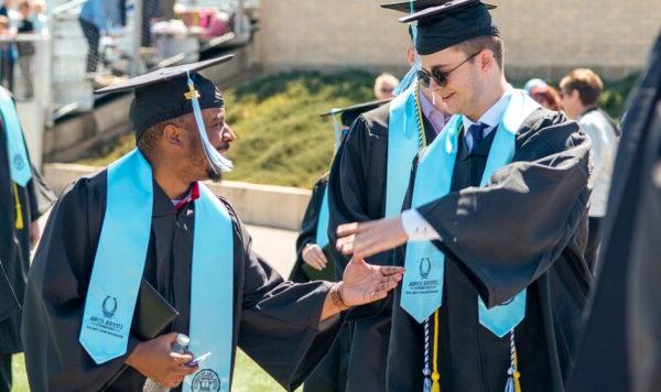 Two 凯发 graduates shake hands at commencement